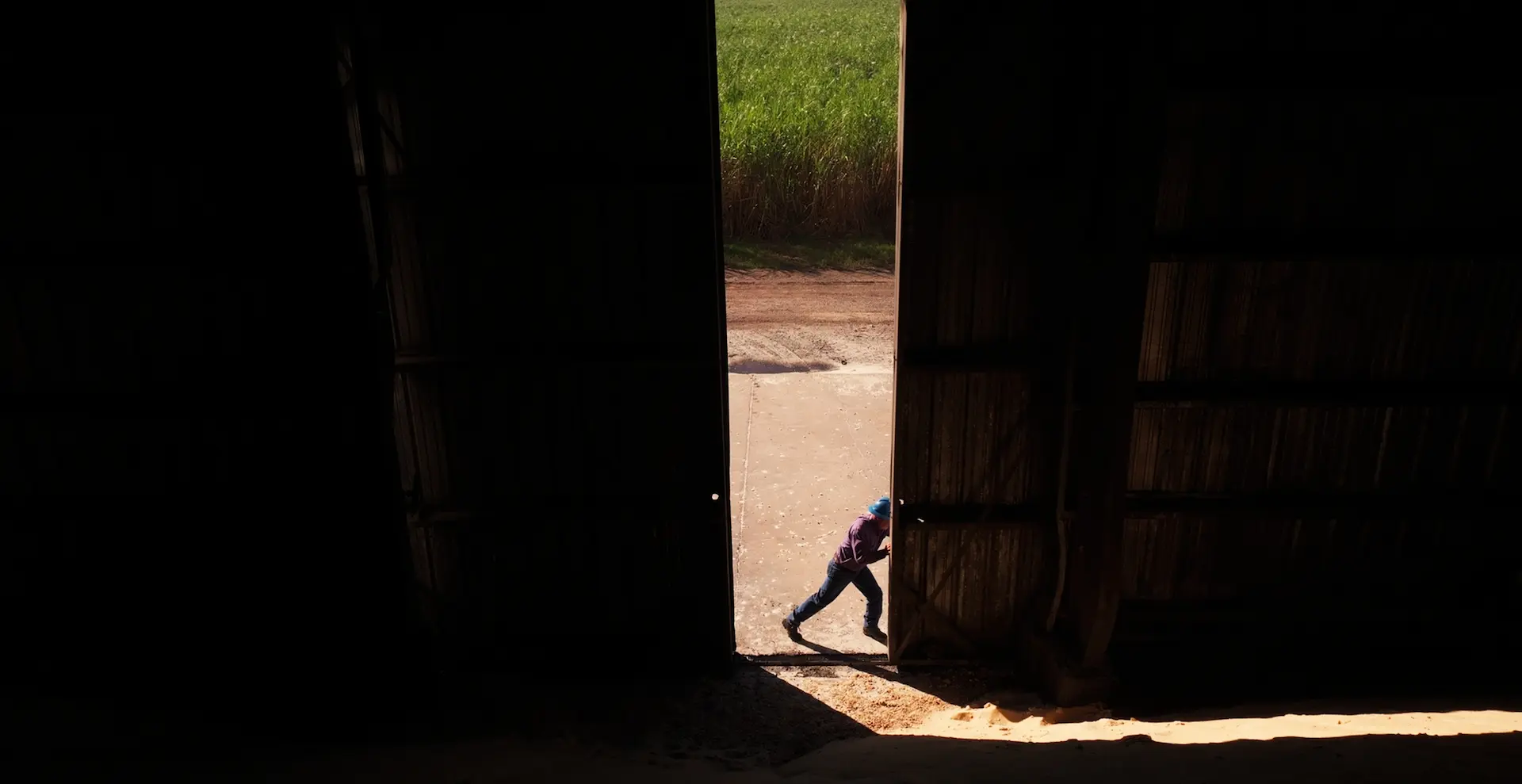Man pushing open the door of a large farm building
